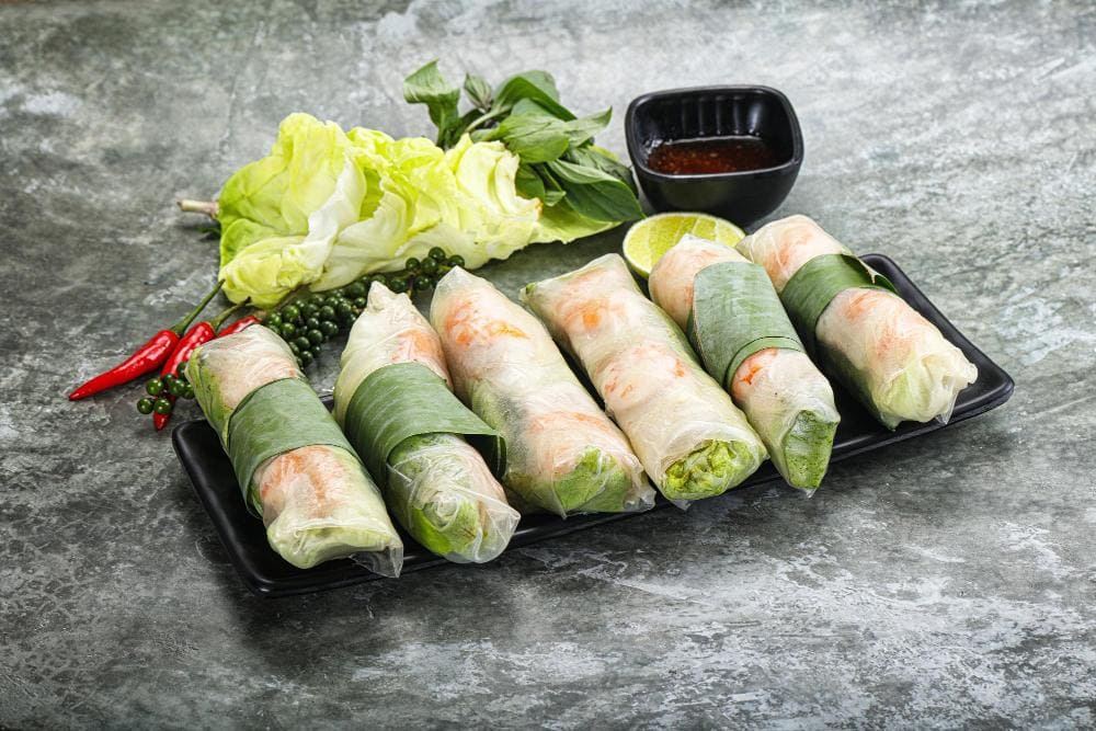 Goi Cuon (Vietnamese Spring Rolls) made from translucent rice paper wrapped around shrimp, sliced pork belly, vermicelli noodles, lettuce, mint, and other herbs